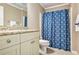 Tiled bathroom features a shower with blue shower curtain, tile flooring, and a granite-topped vanity at 4922 Summer Wind Dr, Buford, GA 30519