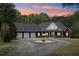 Charming brick home featuring a three-car garage and a circular driveway, nestled among mature trees and sunset skies at 270 Morrow Rd, Newborn, GA 30056
