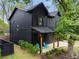 An angle view of a modern home showcasing a welcoming porch, dark exterior, and fresh landscaping at 3172 Chapel St, Scottdale, GA 30079