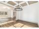 Open-concept living room with modern lighting, hardwood floors, coffered ceiling, and large windows at 400 Stone Lea Trce, Oxford, GA 30054