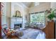 Cozy living room with a fireplace, built-in shelving, and a large window overlooking the backyard at 225 Ansley Close, Roswell, GA 30075