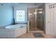 Bright bathroom featuring soaking tub, a decorative window, and a glass enclosed shower at 225 Ansley Close, Roswell, GA 30075