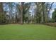 Well-maintained backyard featuring a vast green lawn enclosed by a rustic fence and mature trees at 3983 E Hilda Cir, Decatur, GA 30035