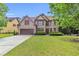 Inviting two-story brick home with a neatly kept lawn, mature trees, and a double-car garage at 2369 Apalachee Crucis Ln, Dacula, GA 30019