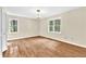 A bright bedroom with hardwood floors, a chandelier, and two large windows at 3175 Old Jonesboro Rd, Fairburn, GA 30213