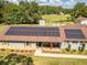 Aerial view showcasing solar panels, a welcoming porch, and a lush green lawn, blending comfort with sustainable energy at 3557 Bill Gardner Pkwy, Locust Grove, GA 30248