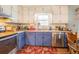 Well-lit kitchen with stainless steel appliances and a red floral rug at 3557 Bill Gardner Pkwy, Locust Grove, GA 30248