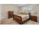 Cozy bedroom features a wooden sleigh bed with cream and gold bedding, soft carpet, and natural light from a window at 4457 Equity Ct, Ellenwood, GA 30294