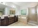 Bright bathroom featuring a double sink vanity, a glass-enclosed shower, and a soaking tub with a decorative window at 133 Newcastle Walk, Woodstock, GA 30188