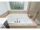 Close up of the soaking tub featuring tile surround, decorative window, and chrome fixtures at 133 Newcastle Walk, Woodstock, GA 30188