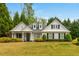 Charming white home featuring a well-manicured lawn and inviting landscaping with mature trees at 133 Newcastle Walk, Woodstock, GA 30188