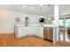 Open kitchen with stainless steel dishwasher, white cabinets and breakfast bar, and wood floors at 133 Newcastle Walk, Woodstock, GA 30188
