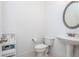 A quaint powder room features a pedestal sink, round mirror and a modern toilet with nearby storage at 133 Newcastle Walk, Woodstock, GA 30188