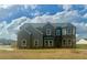 Elegant two-story home with a brick facade and turret-style windows, nestled on a green lawn at 415 Rodeo Dr, Auburn, GA 30102