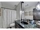 Bathroom with black marble vanity, tiled shower with curtain and modern lighting at 3230 Riverhill Ct, Cumming, GA 30041