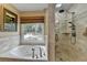 Luxurious bathroom features a soaking tub, separate shower, and tranquil window view at 3230 Riverhill Ct, Cumming, GA 30041