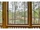 Serene view of a wooded area and pond from a window on a screened porch at 3230 Riverhill Ct, Cumming, GA 30041