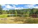 Expansive backyard features a pond with a dock, fire pit, and lush greenery at 325 Brook Hollow Ln, Loganville, GA 30052
