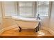 Bright bathroom featuring a claw foot tub with wood floors and large sunny windows at 325 Brook Hollow Ln, Loganville, GA 30052