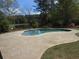 Kidney-shaped pool with surrounding patio and view of wooded backyard at 325 Brook Hollow Ln, Loganville, GA 30052