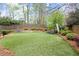 Lush backyard features an artificial lawn, mature trees, and a play area with swing set and soccer net at 383 Indian Hills Trl, Marietta, GA 30068