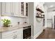 This built-in bar offers glass-front cabinets, a wine cooler, and countertops with shelving that lead to the kitchen at 383 Indian Hills Trl, Marietta, GA 30068