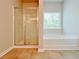 Bright bathroom featuring separate shower and soaking tub, tile floors and a large window for natural light at 5119 Aylesbury Ct, Hoschton, GA 30548