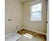 Well-lit laundry room with tiled floor, shelving, and ample natural light from a large window at 5119 Aylesbury Ct, Hoschton, GA 30548