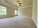 Bright main bedroom featuring carpet floors, tray ceiling, ceiling fan and natural light from many windows at 5119 Aylesbury Ct, Hoschton, GA 30548