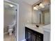 Half bathroom with a toilet, dark cabinets, granite countertop, and decorative mirror at 7130 Rocking Horse Ln, Cumming, GA 30040