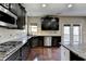 Modern kitchen featuring dark wood cabinets, granite countertops, stainless steel appliances, and hardwood floors at 7130 Rocking Horse Ln, Cumming, GA 30040