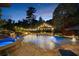 Beautiful in-ground pool with a waterfall feature, fire pit, lounge chairs, and lush landscaping at 332 Chaffin Rd, Roswell, GA 30075