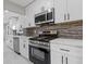 Renovated kitchen with white cabinets, stainless appliances, modern backsplash, and quartz countertops at 4718 Lou Ivy Rd, Peachtree Corners, GA 30096