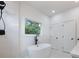Bathroom featuring standalone tub next to a window with nature views, tiled shower, and white doors at 2438 Shadburn Ferry Dr, Buford, GA 30518