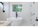 Elegant bathroom with a standalone tub, marble-look tile, and a view of lush greenery through the window at 2438 Shadburn Ferry Dr, Buford, GA 30518