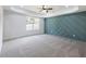 Spacious bedroom with tray ceilings, teal accent wall, and natural light from large window at 2438 Shadburn Ferry Dr, Buford, GA 30518