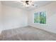 Bright bedroom featuring a ceiling fan, plush carpet, and a window overlooking mature trees at 2438 Shadburn Ferry Dr, Buford, GA 30518