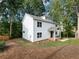 Charming two-story white home boasts a covered front porch, lush landscaping, and mature trees at 2438 Shadburn Ferry Dr, Buford, GA 30518