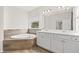 Luxurious bathroom featuring a corner soaking tub with tile surround and a double sink vanity with white cabinets at 4236 Silver Spruce Ln, Smyrna, GA 30080