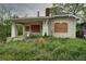 Overgrown front yard of boarded-up bungalow-style home with a brick chimney and covered porch at 1366 Sylvan Sw Rd, Atlanta, GA 30310