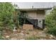 Back exterior of an overgrown, dilapidated house with damaged stairs and debris-filled yard at 1366 Sylvan Sw Rd, Atlanta, GA 30310