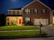 Exterior nighttime view of a two-story brick home with a well-lit lawn at 3798 Broadleaf Walk, Snellville, GA 30039