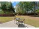 Lush backyard showcasing a seating area, green grass, and a backdrop of mature trees and a wooden fence at 3452 Hard Creek Ln, Buford, GA 30519