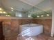 Bathroom featuring a large soaking tub with gold fixtures and mirrored wall at 629 Pinetree Dr, Decatur, GA 30030