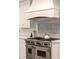 Close up of chef's kitchen featuring stainless steel range, white cabinetry and unique tile backsplash at 3511 Roxboro Ne Rd, Atlanta, GA 30326