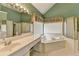 Green bathroom featuring a sunken tub, shower, and decorative window treatment at 220 Carriage Station Dr, Lawrenceville, GA 30046