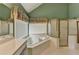 Green bathroom featuring a sunken tub, shower, and decorative window treatment at 220 Carriage Station Dr, Lawrenceville, GA 30046