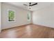 A bright bedroom features hardwood floors, a ceiling fan, and two windows at 100 Maison Ct, Roswell, GA 30076