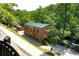 Historic brick mill building with a green metal roof, nestled in a lush green wooded area along the river at 100 Maison Ct, Roswell, GA 30076