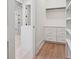 Walk-in closet with white storage cabinets, hardwood floors, and a view of the shower at 100 Maison Ct, Roswell, GA 30076